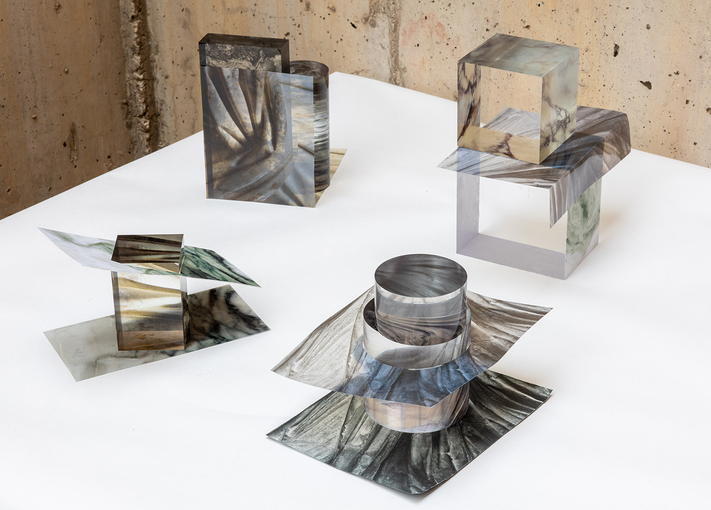 Four constructions of photos intersecting clear glass blocks and cylinders