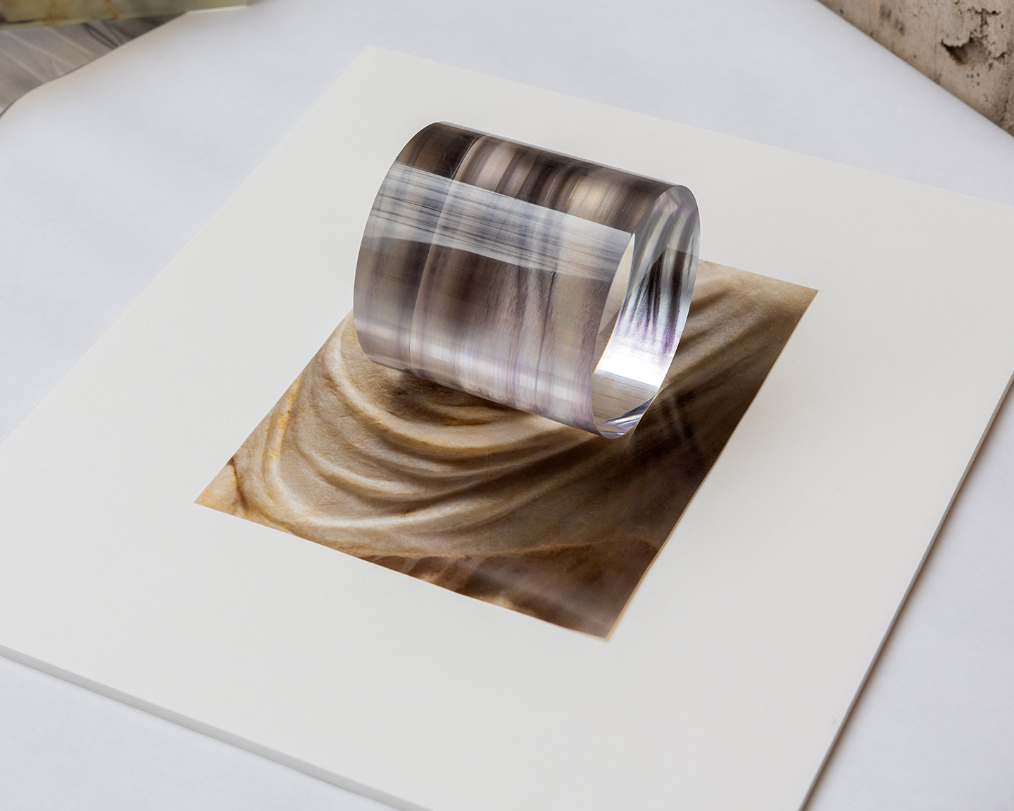 a photo of draped cloth, on a board below a clear plastic cylinder